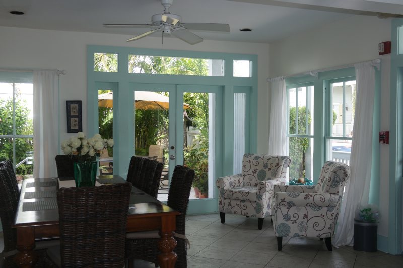 Bright breakfast and common room with teal-trimmed windows looking onto garden