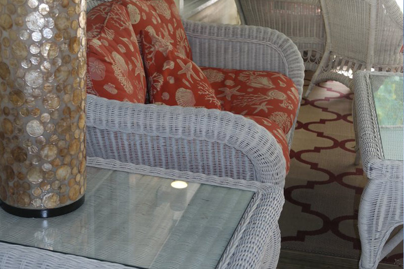 White wicker chair with seashell-print cushions on the porch