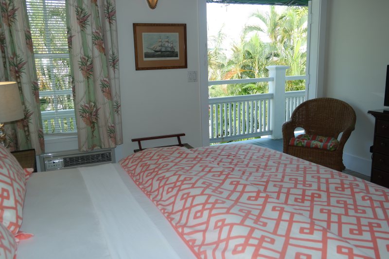Room with open French doors onto balcony with palm views