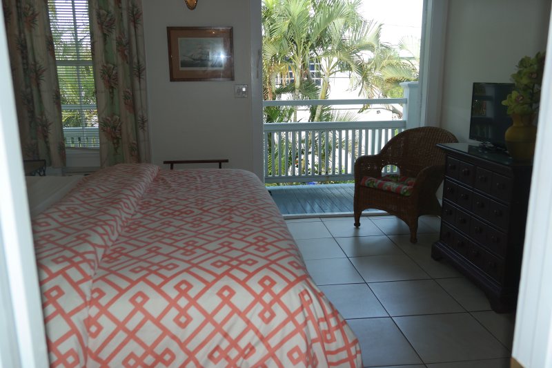 Room with balcony view and wicker chair beside open door