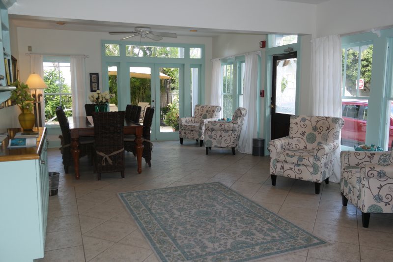 Common room and lobby with teal windows, dining table, and armchairs